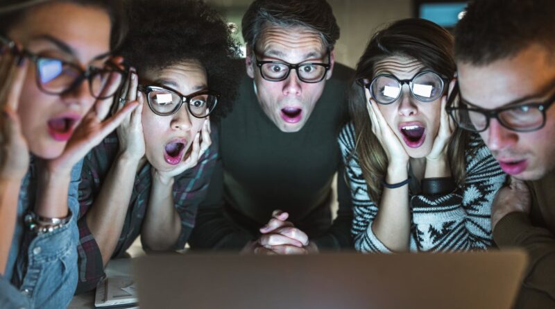Group of shocked-looking people looking at computer screen.